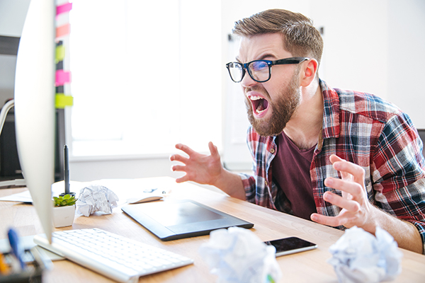 Frustrated man yelling at his computer.