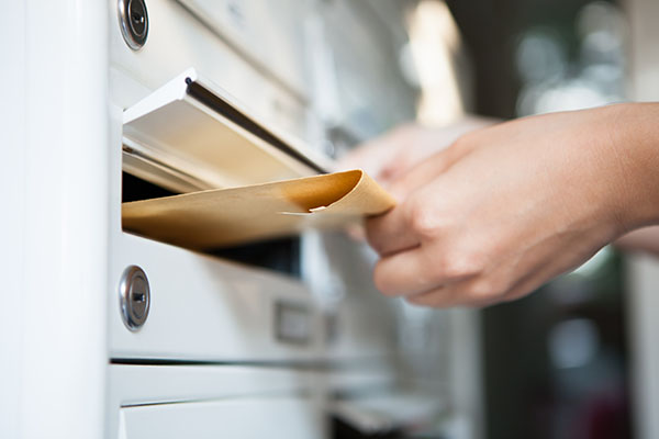 Hand placing mail in a mailbox.